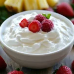 Creamy Yogurt Fruit Dip In A White Bowl Surrounded By Fresh Strawberries, Pineapple, And Kiwi, With A Drizzle Of Honey.
